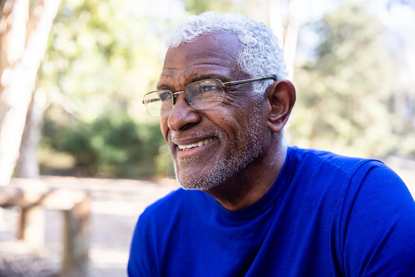 A man with glasses and white hair sitting outside.